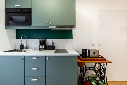 Modern kitchen in Logis Camille apartment at La Maison George, Flavigny sur Ozerain, with sage green cabinets and white tile