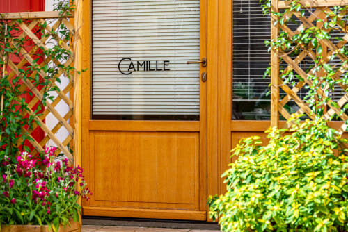 Wooden door entrance to Logis Camille apartment at La Maison George in Flavigny sur Ozerain, flanked by green ivy and pink
