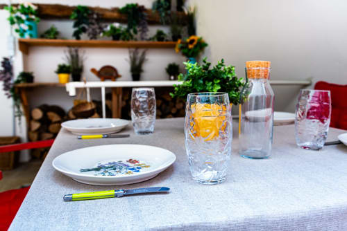 Elegant dining table at La Maison George with place settings, yellow drink, and potted plants in Logis Camille apartment.