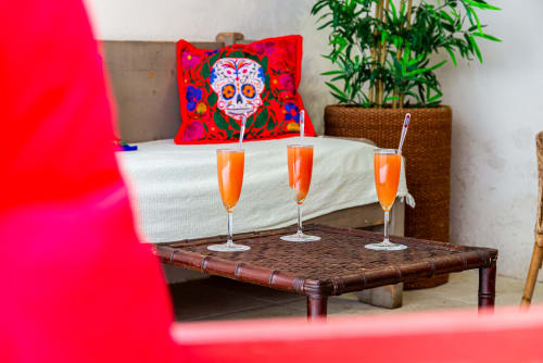 Colorful bohemian bedroom at La Maison George with orange cocktails, skull pillow, and bamboo plant