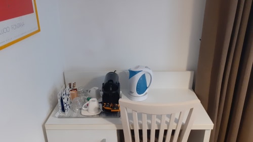 Scrivania con caffettiera, bollitore e servizi nella suite Michelangelo Roma con letto matrimoniale