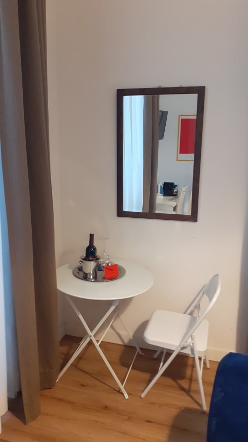 Vanity con specchio nella Michelangelo Suite Roma, con sedia bianca e esposizione di bottiglie di vino