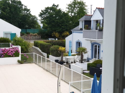 Appartement en bord de mer avec architecture bleu et blanc, terrasse avec sièges, fleurs roses à Locmaria Belle Île en Mer