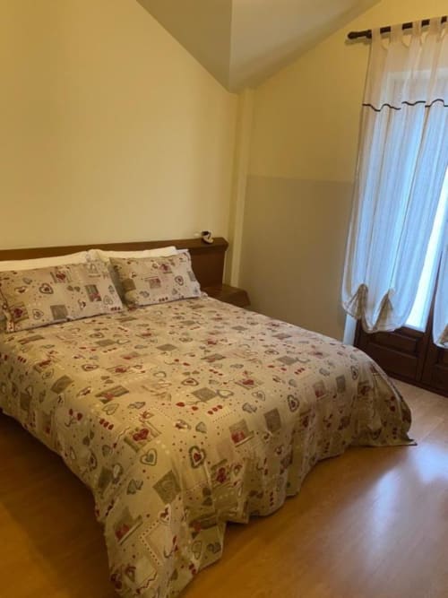 Cozy Standard Double Room at Hotel Le Clou in Arvier with cream bedding, yellow walls, wooden floors, and natural light from