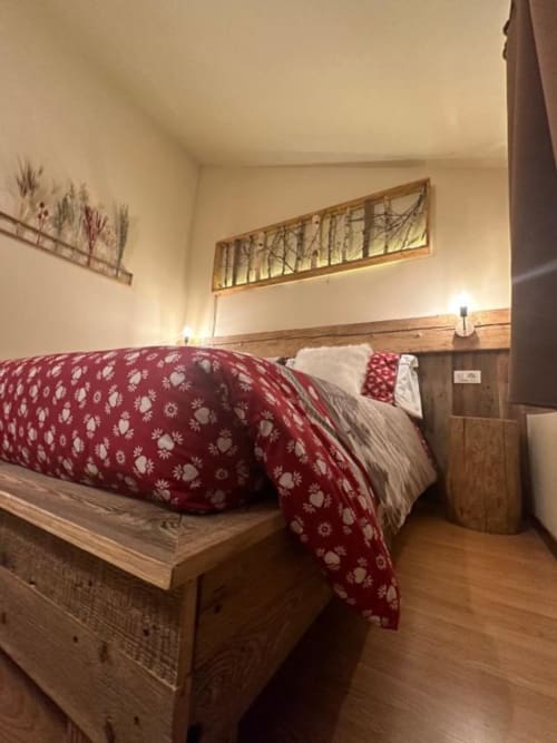 Superior King Room at Hotel Le Clou in Arvier with burgundy bedding, wood furnishings, and warm lighting