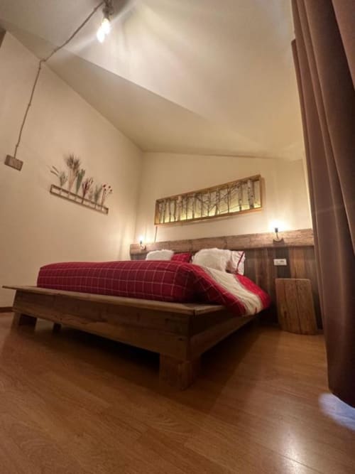 Superior King Room at Hotel Le Clou in Arvier with wooden bed, red bedding, sloped ceiling, and parquet flooring