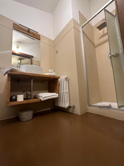 Modern bathroom in Superior King Room at Hotel Le Clou, Arvier, with wooden vanity, round sink, mirror, and glass shower