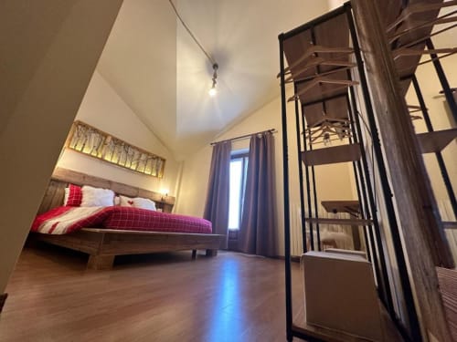 Superior King Room at Hotel Le Clou with wooden bed, loft ladder, wood flooring, and city view in Arvier