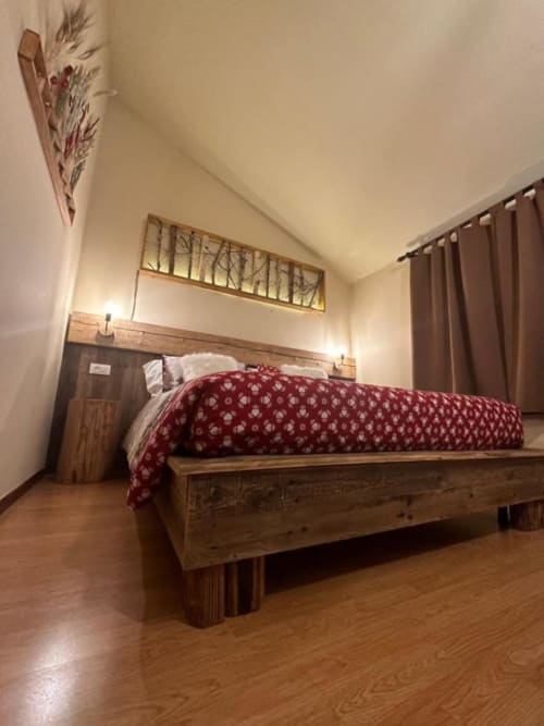 Spacious Superior King Room at Hotel Le Clou in Arvier with wooden bed, red bedding, warm lighting, and wood flooring
