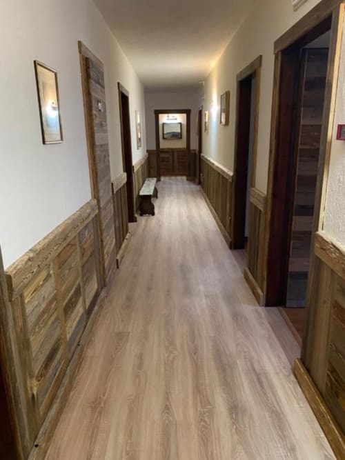 Long hallway at Hotel Le Clou in Arvier with wooden wainscoting, multiple doors, and warm lighting