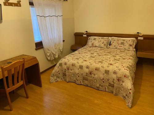 Camera doppia standard all'Hotel Le Clou di Arvier con letto in legno, scrivania e pavimento in parquet