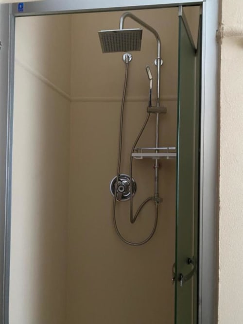 Modern shower enclosure with rainfall showerhead and handheld spray at Hotel Le Clou in Arvier