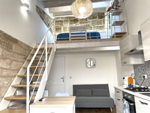Modern loft apartment at Catalogna10 in Alghero with mezzanine bed, spiral stairs, open kitchen, and city view