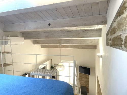 Modern loft bedroom at Catalogna10 in Alghero with exposed beams, mezzanine, and city view