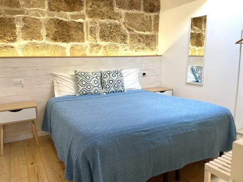 Modern bedroom at Catalogna10 Rooms in Alghero with blue bedding, stone wall, and wooden floors