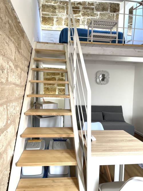 Wooden staircase in Catalogna10 loft apartment, Alghero, with storage below and city views above