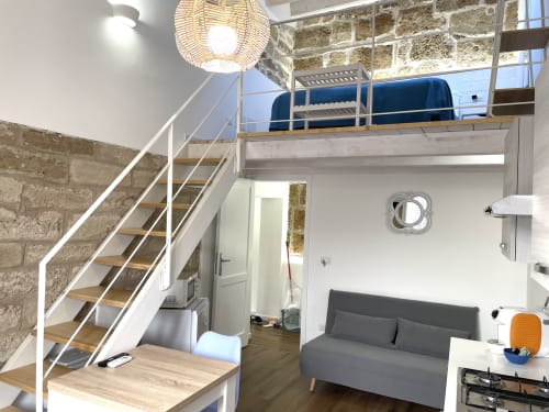 Modern loft apartment at Catalogna10 in Alghero with mezzanine bedroom, spiral stairs, and gray sofa