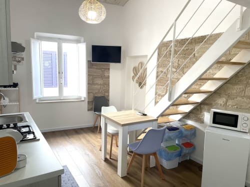 Modern apartment at Catalogna10 in Alghero with open-plan kitchen, dining area, and wooden staircase