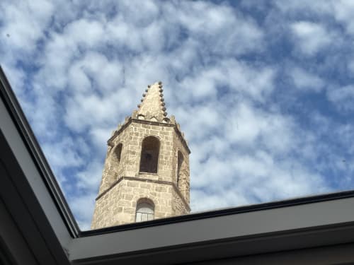 Historic stone church bell tower against blue sky, viewed from Catalogna10 Rooms in Alghero