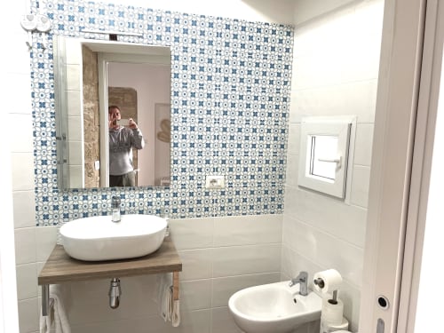 Modern bathroom at Catalogna10 Rooms in Alghero with blue patterned tiles, vessel sink, and mirror