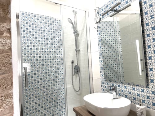 Modern bathroom at Catalogna10 Rooms in Alghero with blue geometric tile shower, round sink, and mirror