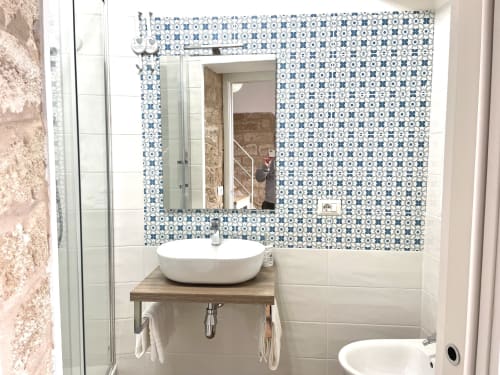 Modern bathroom with blue patterned tiles, white sink, mirror, and shower at Catalogna10 in Alghero