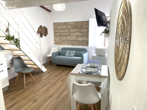 Modern apartment interior at Catalogna10 Rooms e Loft in Alghero with teal sofa, dining area, wooden floors and decorative