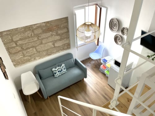 Modern studio apartment at Catalogna10 in Alghero with teal sofa, pendant lamp, and city views