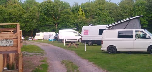 Postwood Gardens Campsite in Kentisbeare with camper vans parked on grassy pitches among trees