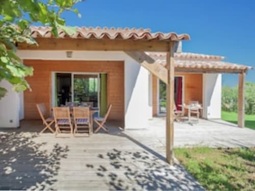 Terrasse de la villa Le Maquis Plage avec mobilier de jardin en bois, pergola et vue sur mer à Poggio-Mezzana