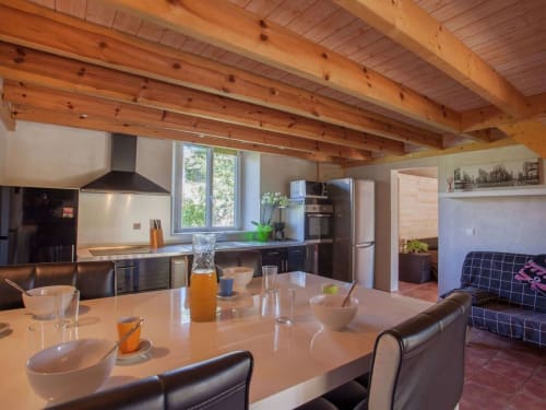 Cuisine ouverte et salle à manger de la villa Le Maquis Plage avec poutres en bois apparent, électroménagers modernes et terracotta