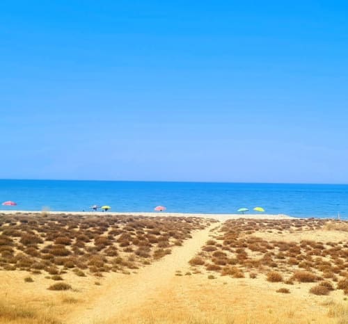 Sentiero sulla spiaggia sabbiosa con ombrelloni colorati, mare e cielo blu presso Le Vajane B&B a Torino di Sangro, Italia