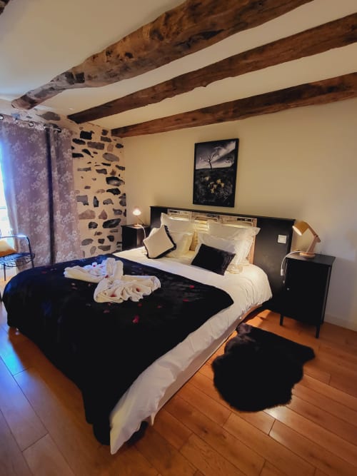 Chambre zen au Mas De Rigoulac avec poutres apparentes, mur en pierre et vue sur le jardin à Argences-en-Aubrac