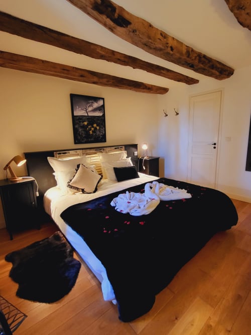 Chambre zen au Mas de Rigoulac avec literie noir et blanc, poutres apparentes, œuvres d'art vue jardin et ambiance chaleureuse