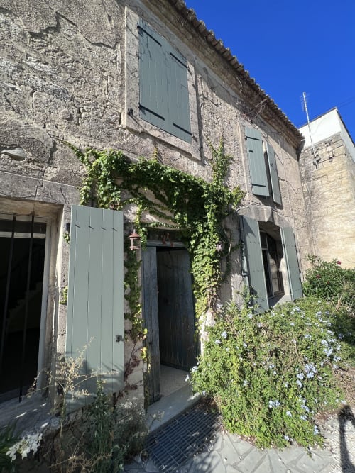 Stone villa entrance with green shutters and ivy-covered doorway in Boissieres, France