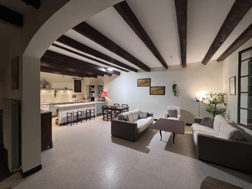 Modern villa living room at La Conciergerie De Franck with exposed beam ceiling, comfortable seating, dining area, and open