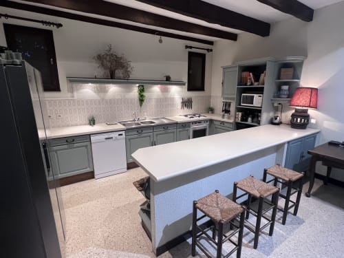 Modern villa kitchen with blue island, white countertops, and dining area at La Conciergerie De Franck, Boissieres