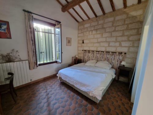 Rustic bedroom at La Conciergerie De Franck villa in Boissieres with terracotta floors and stone walls