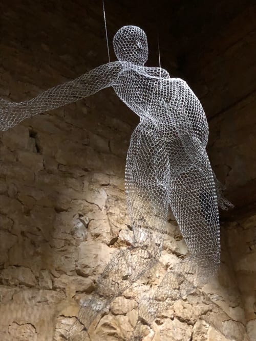 Sculpture en treillis métallique d'une figure humaine contre un mur de pierre au Domaine de l'Ocrerie, Pourrain France