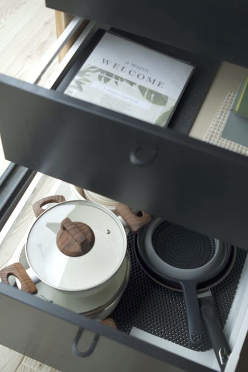 Kitchen drawer at Villa Várzea displaying cookware with white pot, lid, and strainer on black mat