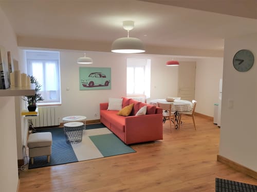 Appartement moderne et spacieux à la Conciergerie Des Climats à Beaune avec canapé corail, coin repas et œuvre d'art voiture vintage