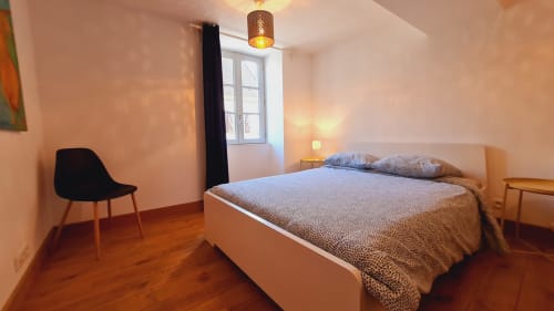 Chambre moderne à la Conciergerie Des Climats à Beaune avec lit blanc, parquet, chaise noire et vue sur la ville