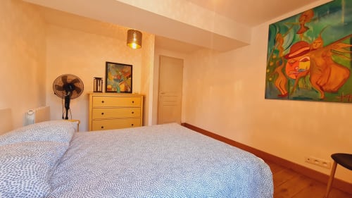 Chambre lumineuse du gîte à Beaune avec lits jumeaux, commode jaune et œuvres colorées à la Conciergerie Des Climats
