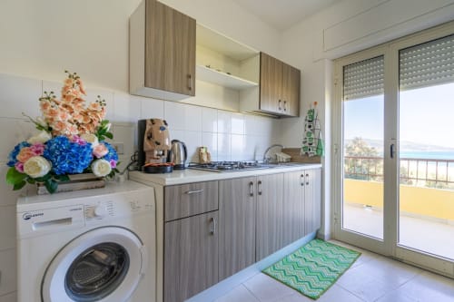 Cucina moderna nell'appartamento Marina di Strongoli con vista mare, fornello a gas, lavatrice e accesso al balcone