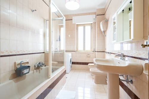 Bagno moderno con doppi lavabi, cabina doccia in vetro e finestre con vista sul mare nell'appartamento Lux Immobiliare a Marina di