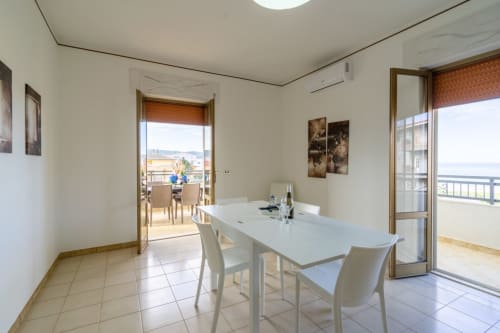 Luminosa zona pranzo in appartamento fronte mare a Marina di Strongoli con vista sul mare attraverso porte in vetro e accesso al balcone