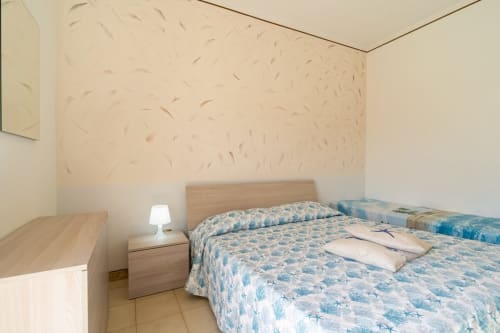 Camera luminosa con due letti gemelli e biancheria blu decorata nell'appartamento fronte mare di Marina di Strongoli