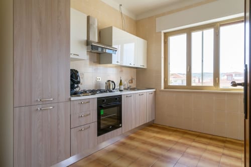 Cucina moderna con mobili in legno chiaro, elettrodomestici in acciaio inox e finestre con vista mare nell'appartamento di Marina di Strongoli