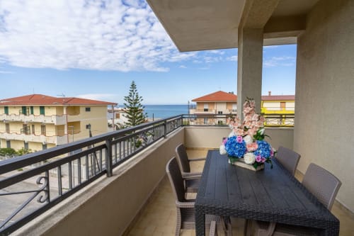 Terrazza con vista mare a Lux Immobiliare a Marina di Strongoli con tavolo da pranzo e fiori colorati affacciati sul Mediterraneo