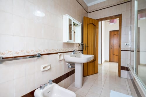Bagno moderno con lavabo a colonna, pareti piastrellate e porte in legno presso Lux Immobiliare Marina di Strongoli